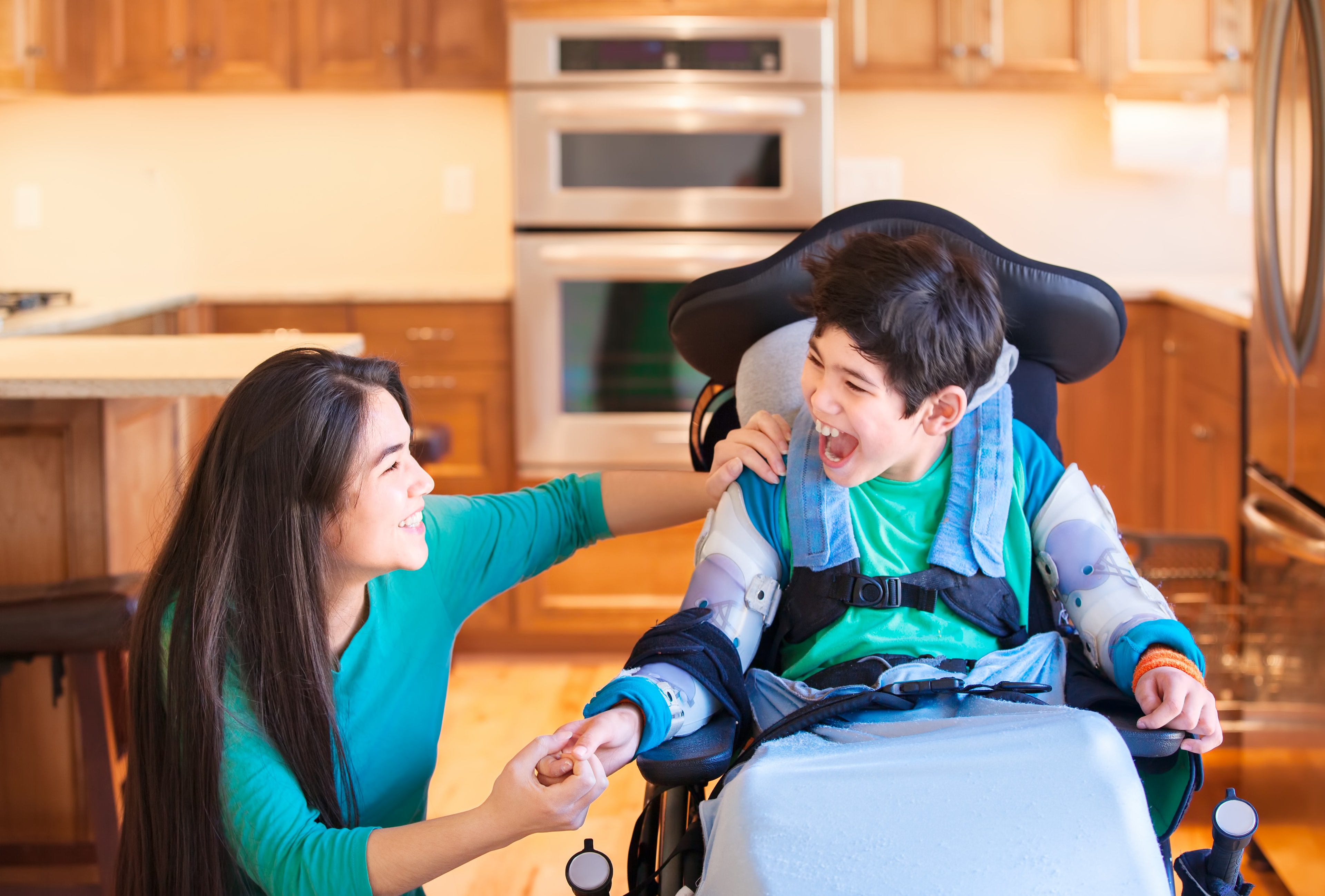 Caregiver sharing a joyful moment with a child in a wheelchair at home